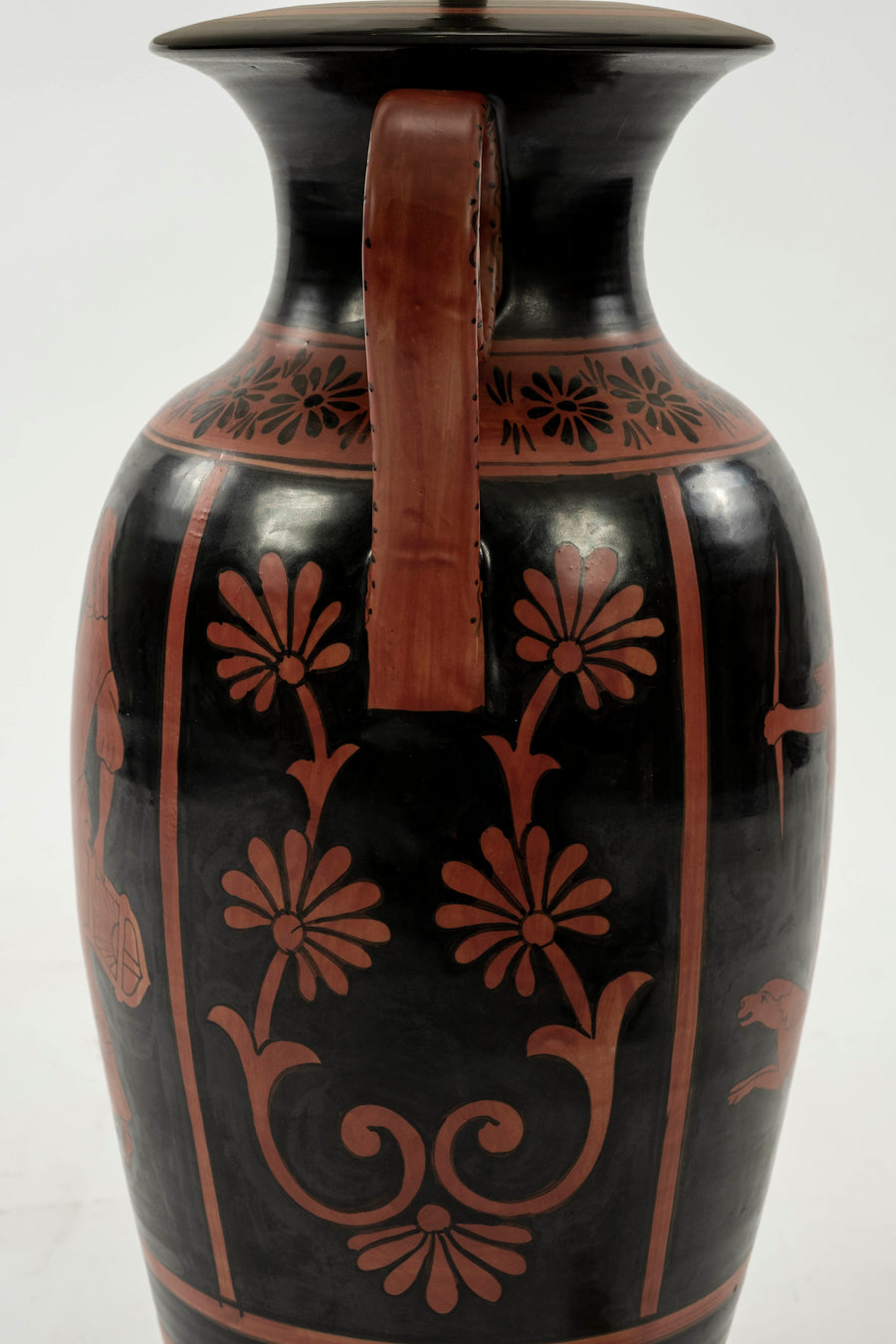 Up-close of the urn lamp's base from the side featuring classic Etruscan-style floral decoration painted in classic red on black.