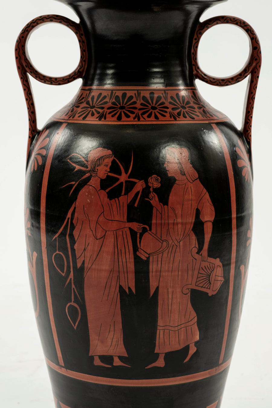 Up-close of the urn lamp's base featuring classic Etruscan artwork of two females conversing while carrying flora and objects from the Etruscan period, painted in classic red on black.